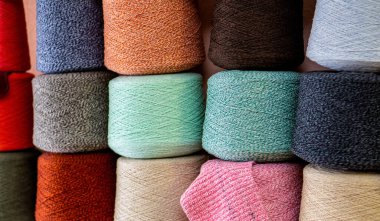 Birbirinin üzerine yığılmış çok renkli iplik parçaları yan yana sıkıca duruyor. Parlak arkaplan.