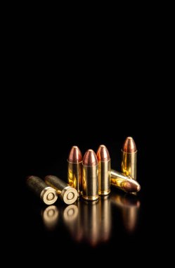 Pistol fişekleri 9 mm 'lik pürüzsüz, parlak bir yüzeyde yansımaları var. Koyu arkaplanda tabancalar ve PCC karabinalar için mühimmat.