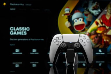 August 7, 2022, Odessa, Ukraine. White new Playstation 5 gamepad with Playstation Plus on screen, selective focus. Classic games. Dark background.