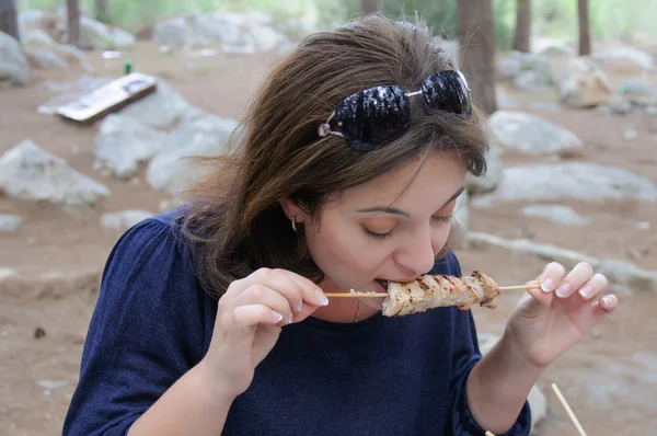 Kvinna biter en grillad kebab — Stockfoto