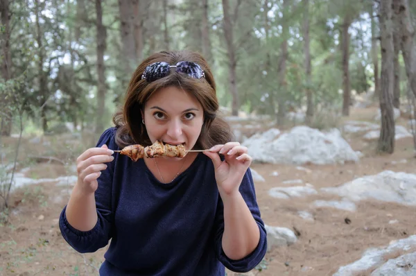 Woman bites a grilled kebab — Stock Photo, Image