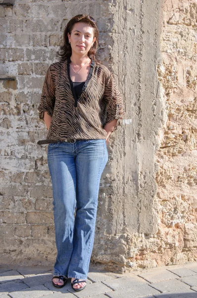 Beautiful woman against stone wall — Stock Photo, Image