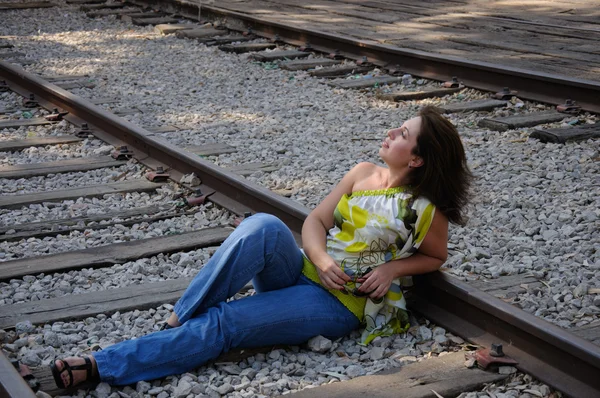 Young traveling woman sitting with suitcase along the train trac — Stock Photo, Image