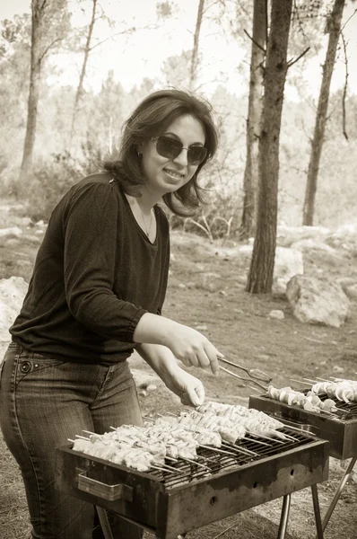 Mujer cocinando carne en sepia barbacoa portátil —  Fotos de Stock