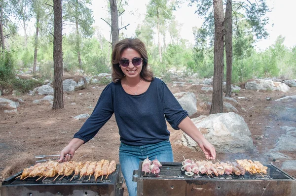 woman cooking meat on portable barbecue