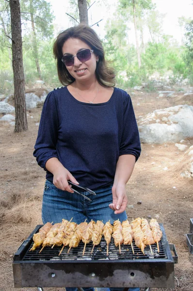 Mujer cocinar carne en barbacoa portátil — Foto de Stock