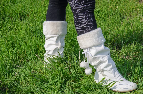 Pernas em meias pretas e botas brancas na grama verde — Fotografia de Stock