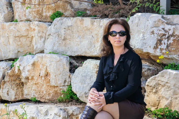 Молодая элегантная женщина сидит снаружи на камнях — стоковое фото