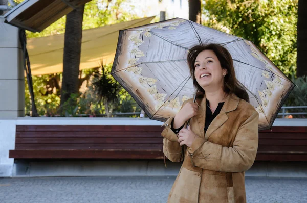 Beautiful young woman in a park with umbrella — Stock Photo, Image