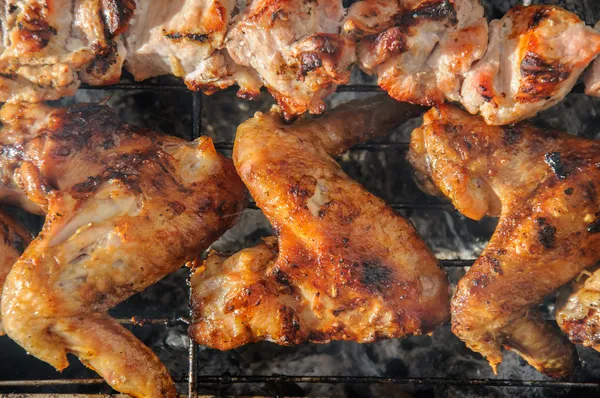 Ailes de poulet et kebabs grillés juteux et sur le barbecue — Photo