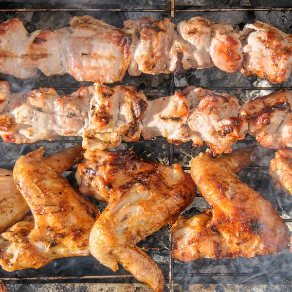 Alitas de pollo y jugosos kebabs asados y en la barbacoa — Foto de Stock