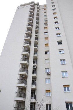Skyscraper, blue sky and birds in the frog perspective.Tall block of flats from the 20th century with 27 floors  from frog perspective with alignment lines.Windows and facade on a sunny day.