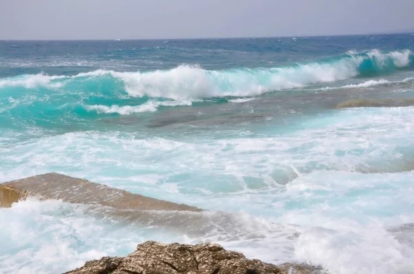 Dramatic Adriatic Sea with waves crashing at Mali Losinj island coast. Perfect rolling wave crash into Croatian beach at island Losinj.  A big wave overlaps the coast of the Croatian island of Losinj. Rolling wave crashing on rocky coast.