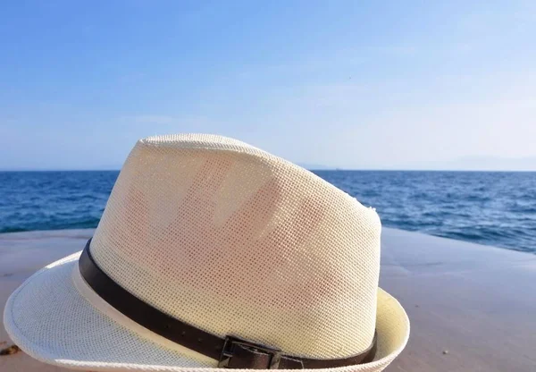 white sun hat on the tropical beach. Beach hat lying on the sand by the sea