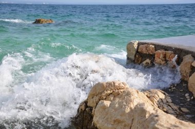 Yazın başında bir Hırvat plajında el sallama. Rijeka sahilindeki kayalıklara vuran dalgalar. Pecine. Deniz, büyük dalga ve taşların üzerine sıçrama.