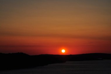Hırvatistan 'ın Mali Losinj kentinde Kızıl Gün Batımı. Güneş, Hırvatistan' ın Losinj adasında kırmızı top olarak batıyor. Adriyatik Denizi 'nin yarattığı toz, gün batımında güçlü bir kırmızı parıltı yaratan havada parçacıklara neden olur..