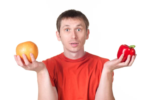 Молодой человек держит в руке свежий перец и грейпфрут — стоковое фото