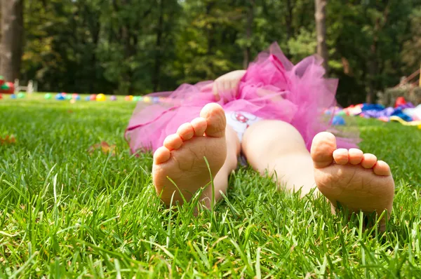 Happy little girl lying on green grass — Stock Photo, Image