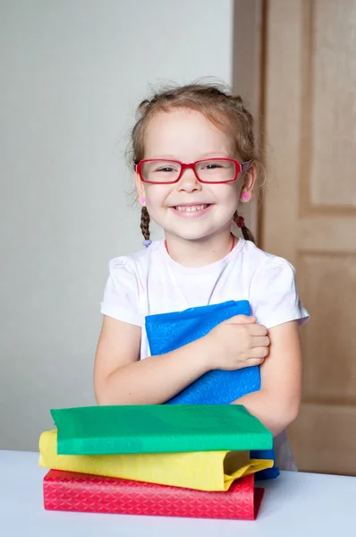 Carino bambina sta leggendo un libro con gli occhiali — Foto Stock