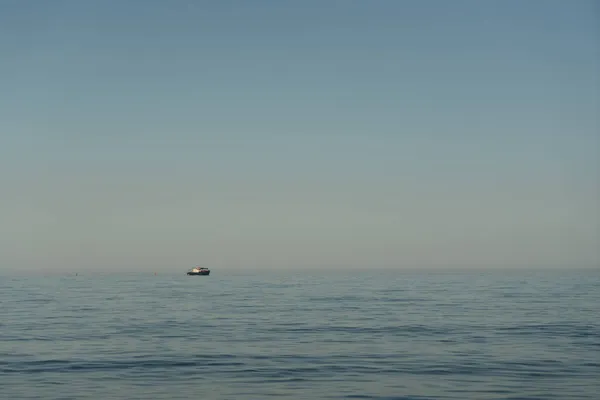 Gün doğumunda ufukta küçük bir deniz teknesi beliriyor.. — Stok fotoğraf