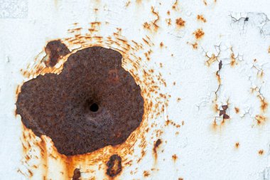 Beyaz boyanmış metal levhada ateşli silah deliği. Metalin doğal yaşı. Pas