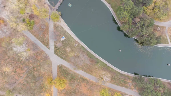 Sétányok és gyalogutak a városi parkban ősszel. Levél hullik a parkba. Őszi tó. Légi felvétel. — Stock Fotó