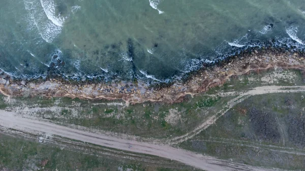 Kaya sahili, dalgalar, toprak yol. Hava görüntüsü. Hava fotoğrafçılığı.