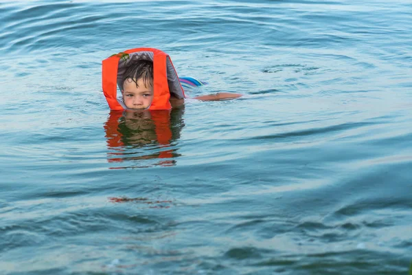 ライフジャケットの助けを借りて海の水の上に5歳の男の子が保持されます — ストック写真