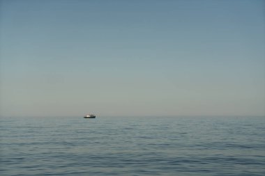 Gün doğumunda ufukta küçük bir deniz teknesi beliriyor..