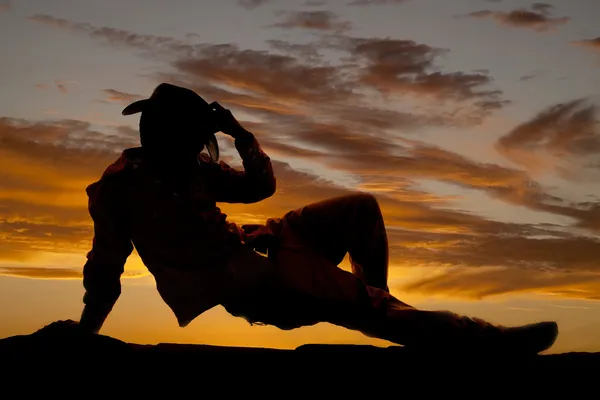 Cowboy på marken håller hatt siluett — Stockfoto