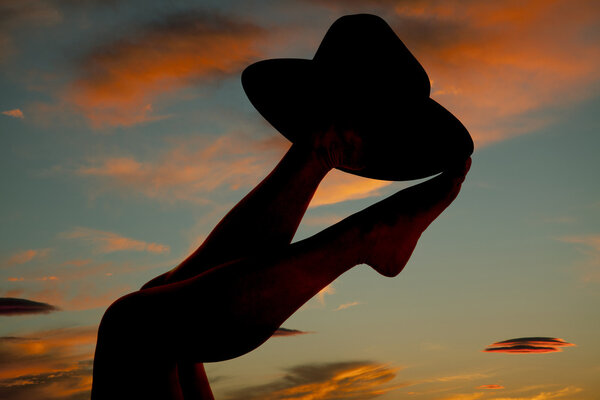 Silhouette woman feet cowboy hat up