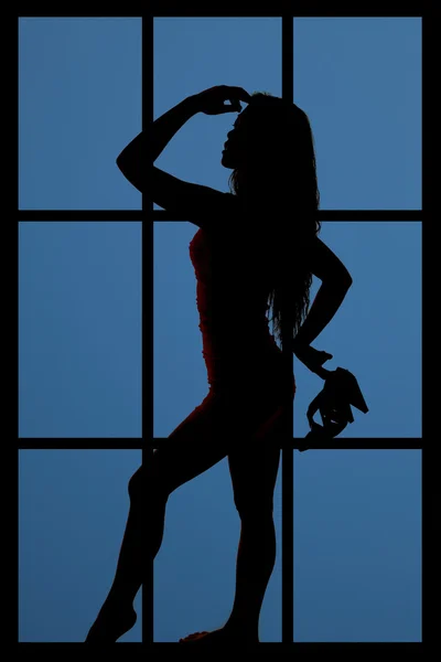 woman in window holding shoes silhouette