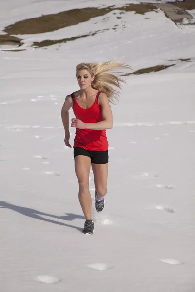 Mulher correr no topo vermelho na neve — Fotografia de Stock