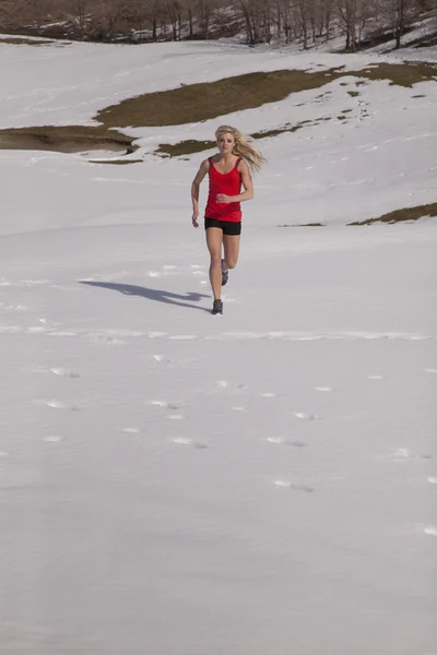 Mujer corriendo en la parte superior roja nieve — Foto de Stock