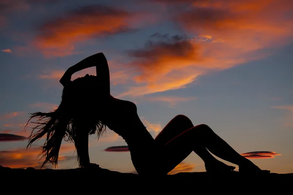 Silhouette di una donna seduta appoggiata al tramonto — Foto Stock