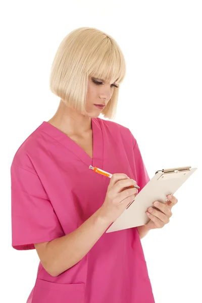 Nurse in pink scrubs writing — Stock Photo, Image