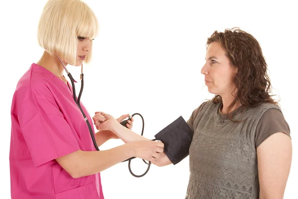 Медсестра измеряет артериальное давление женщины — стоковое фото