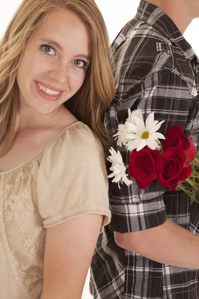 Woman smile back against man holding flowers — Stock Photo, Image