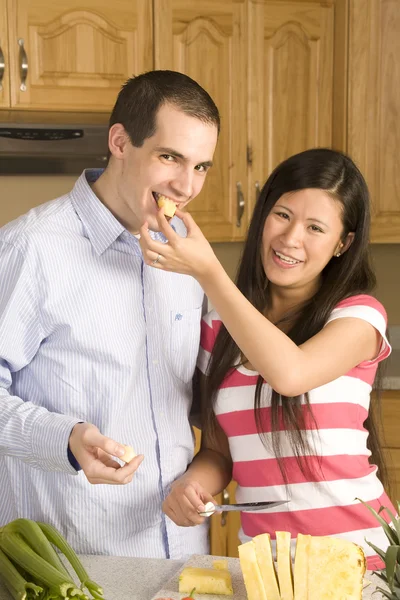 Wife feeding her husband a bite of pineapple — Stock Photo, Image