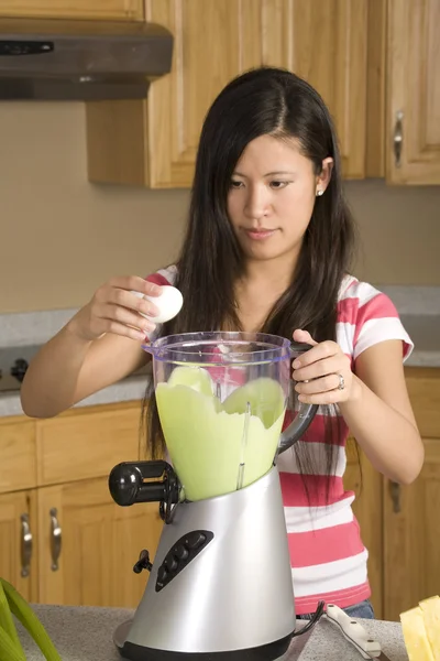 Woman placing ingredients into her healthy smoothie — Stock Photo, Image