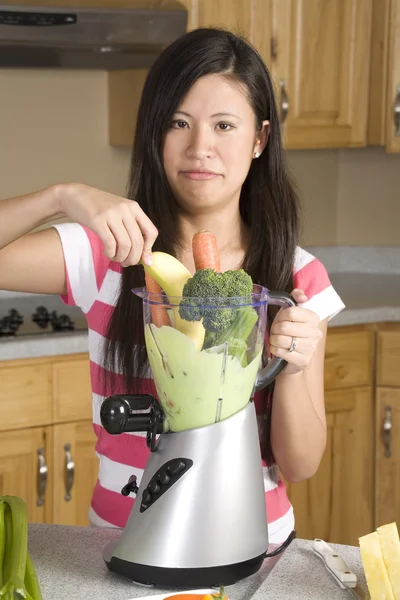 Donna mettendo ingredienti nel suo frullato sano — Foto Stock