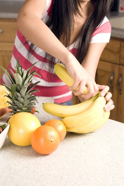 Mujer poniendo su mano en su bolso sacando sus frutas y verduras y poniéndolas en su mostrador de cocina . —  Fotos de Stock