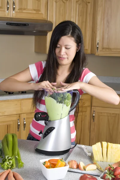 Femme plaçant des ingrédients dans son smoothie sain — Photo