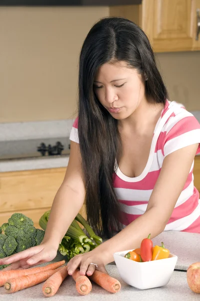 Mujer poniendo su mano en su bolso sacando sus frutas y verduras y poniéndolas en su mostrador de cocina . — Foto de Stock