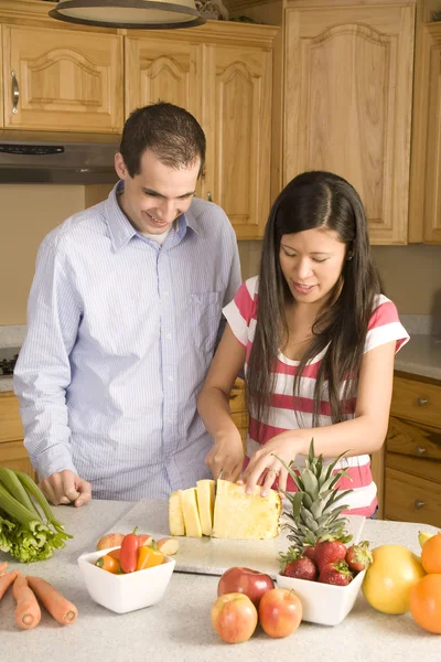 Pareja en la cocina cortando una piña . — Foto de Stock