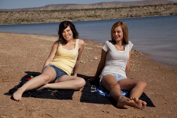 Frauen sitzen und entspannen auf ihren Handtüchern am Strand — Stockfoto