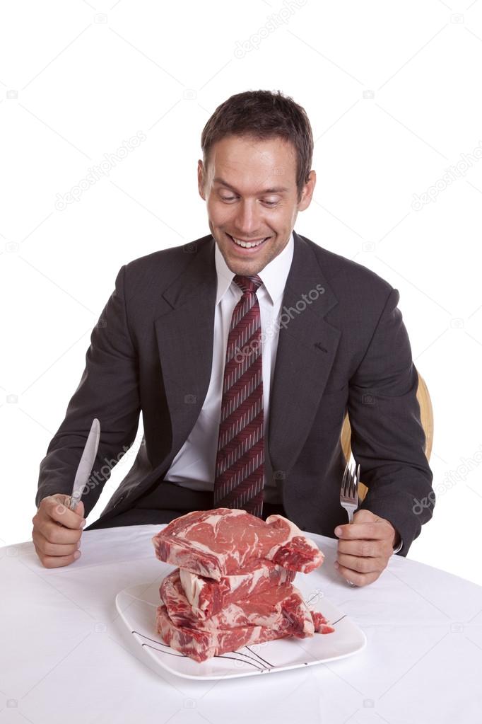 Man smiling at pile of steaks