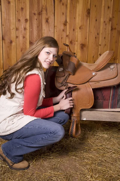 Woman crouching by saddle — Stock Photo, Image