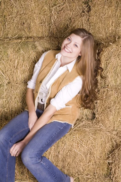 Женщина на стоге сена с улыбкой на голове — стоковое фото