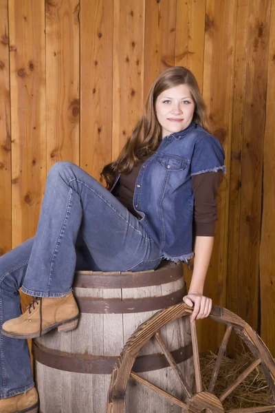 Woman sitting on barrel with wagon wheel — Stock Photo, Image